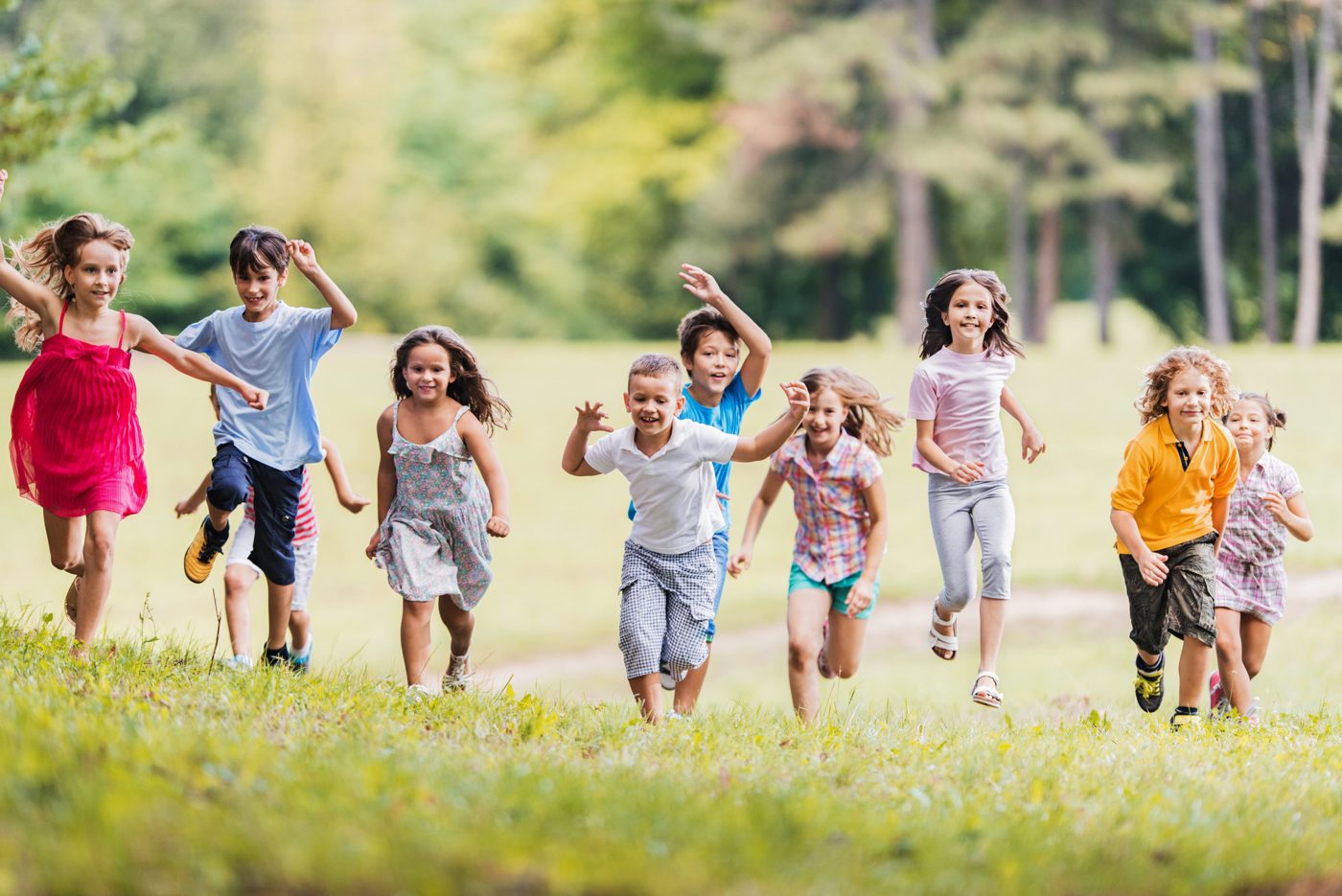 Kinder laufen gemeinsam drau&szlig;en &uuml;ber eine Wiese